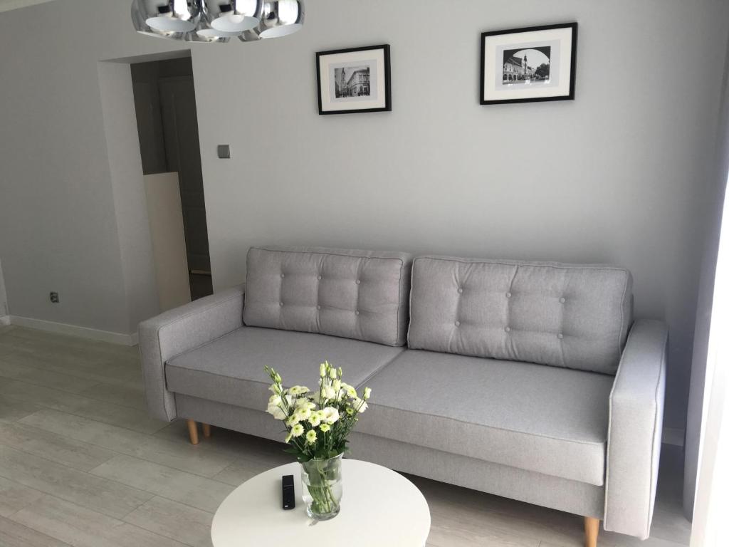 un soggiorno con divano e tavolo con fiori di Mg Apartamenty - Apartament 51 a Oświęcim