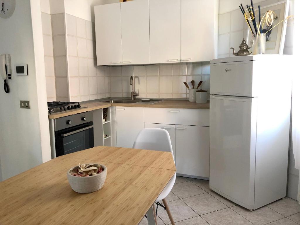 La Casina di Zaira في ريميني: مطبخ مع طاولة خشبية وثلاجة بيضاء