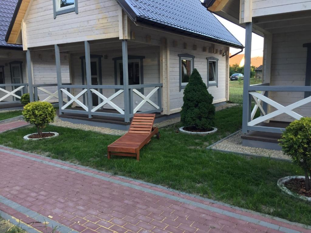 a wooden bench sitting in the grass in front of a house at Świerkowy Zakątek in Sztutowo