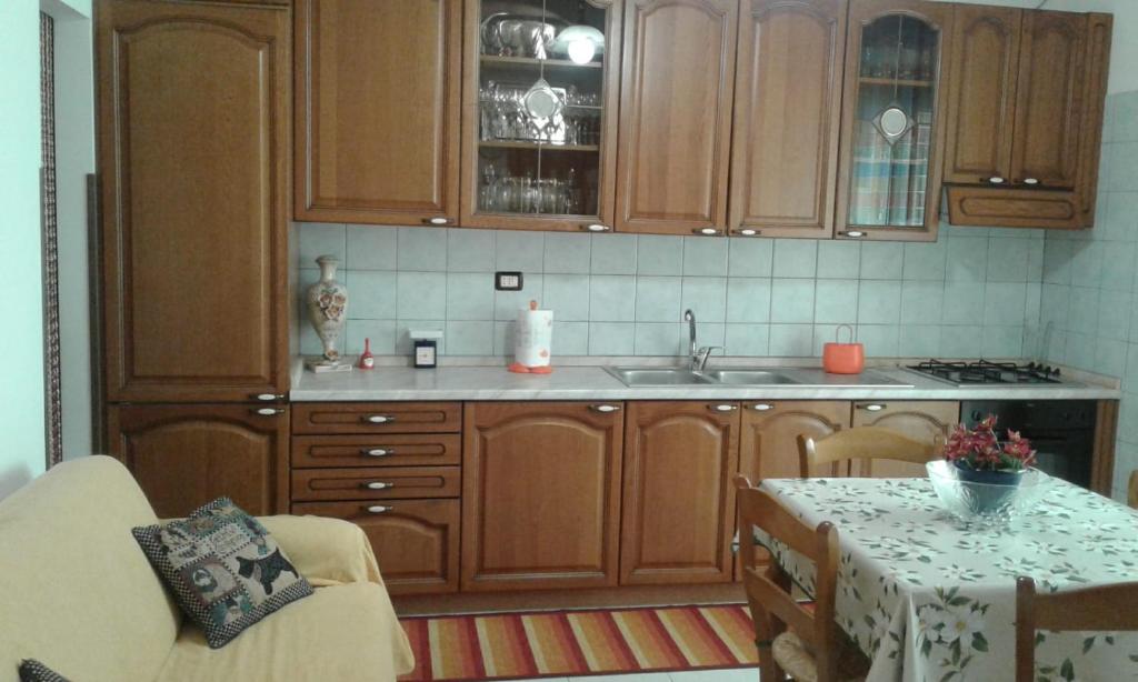 una cocina con armarios de madera, mesa y fregadero en Casa Marianna, en Alcamo