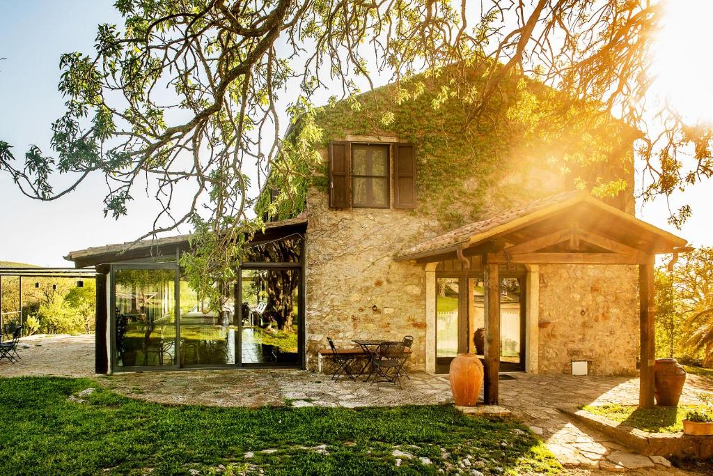 a stone house with glass doors and a tree at Agriturismo Bio Le Macchie Alte in Manciano