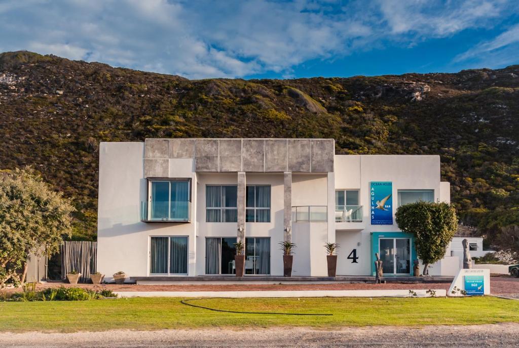 a white building with a mountain in the background at Agulhas Ocean House in Agulhas