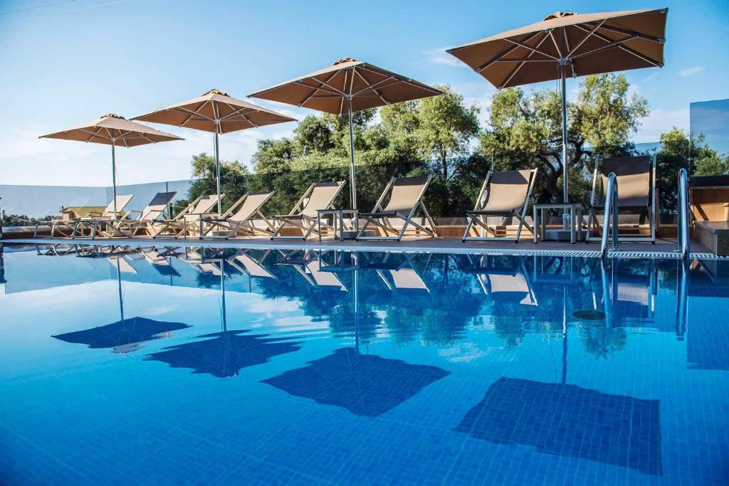 a swimming pool with chairs and umbrellas at Panorama Exclusive Suites in Parga