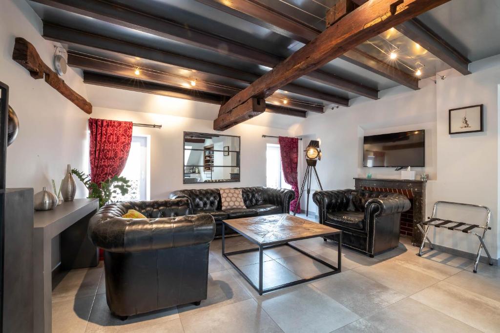 a living room with leather furniture and a table at La Maison de Maurice in Beaune