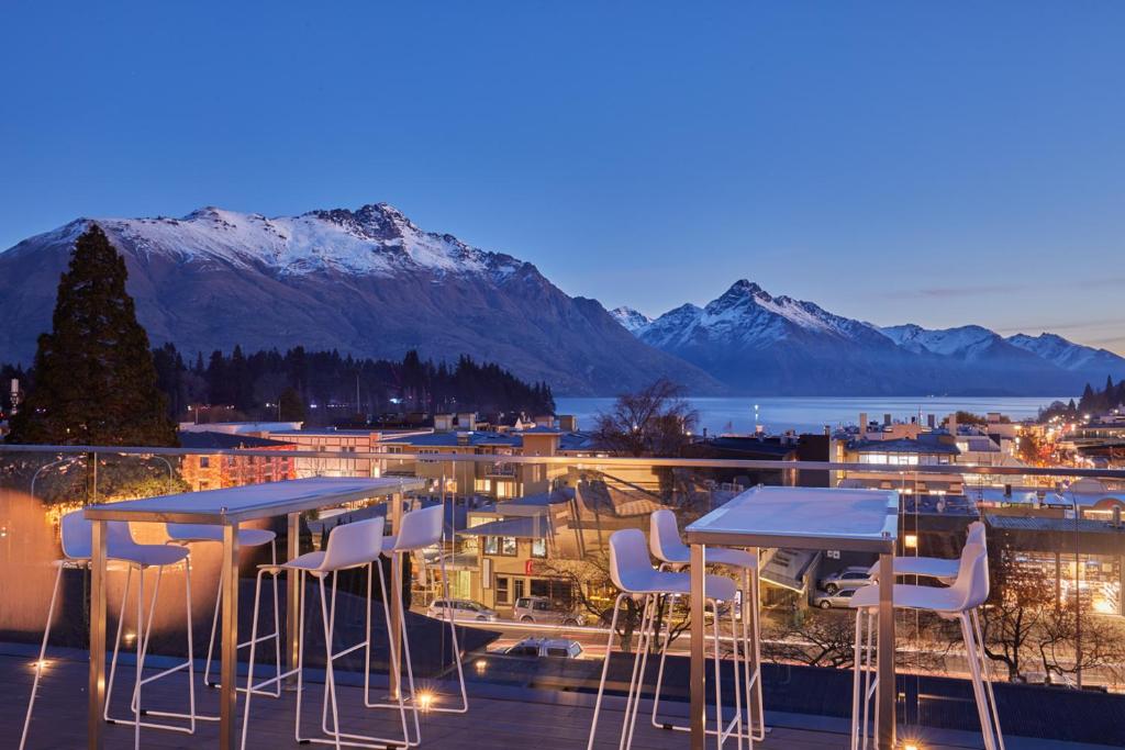 een tafel en stoelen op een balkon met uitzicht op de bergen bij mi-pad Queenstown in Queenstown