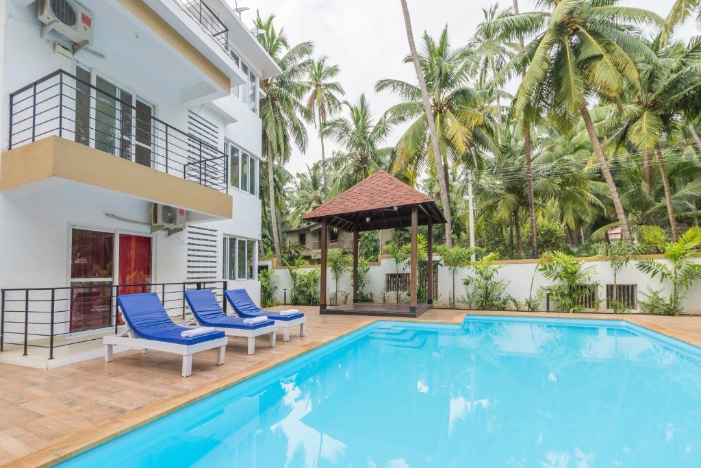 a villa with a swimming pool and palm trees at Rainforest Enclave, Arpora - 10 mins to Baga beach in Arpora