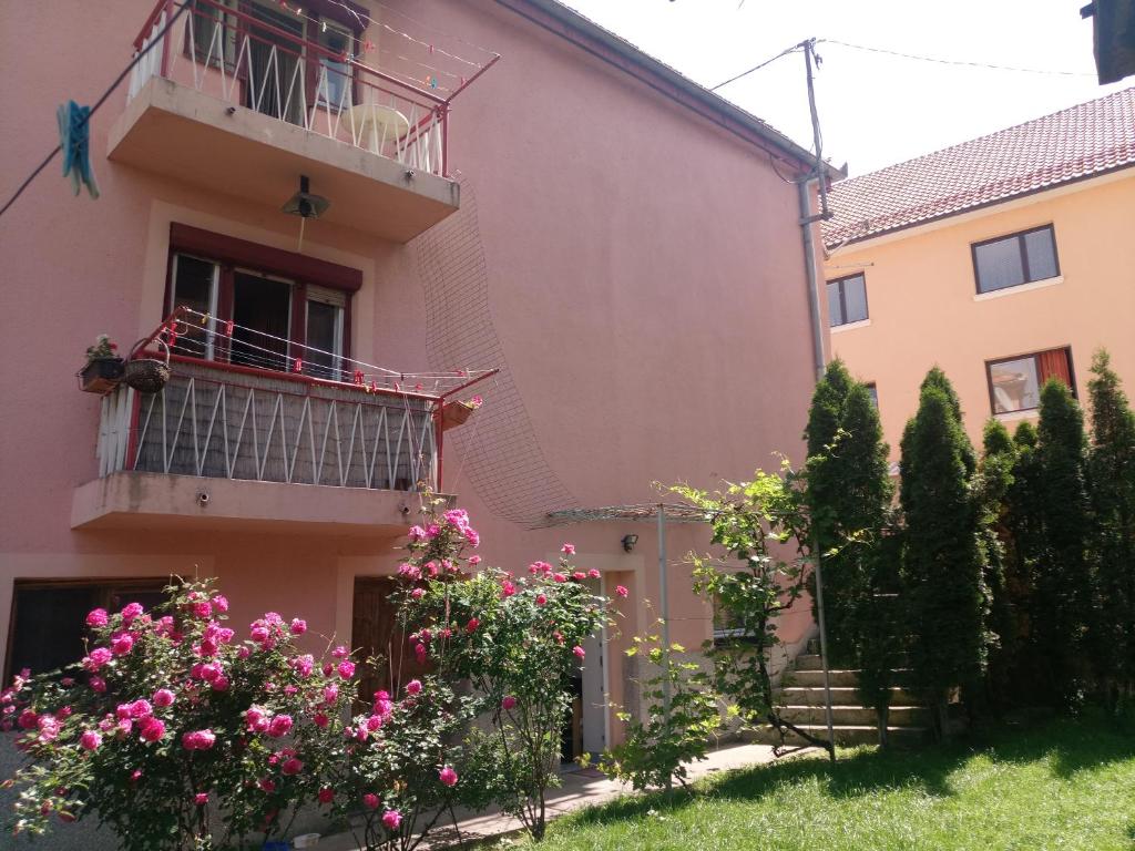 a pink house with a balcony and flowers at Apartmani Konta in Livno