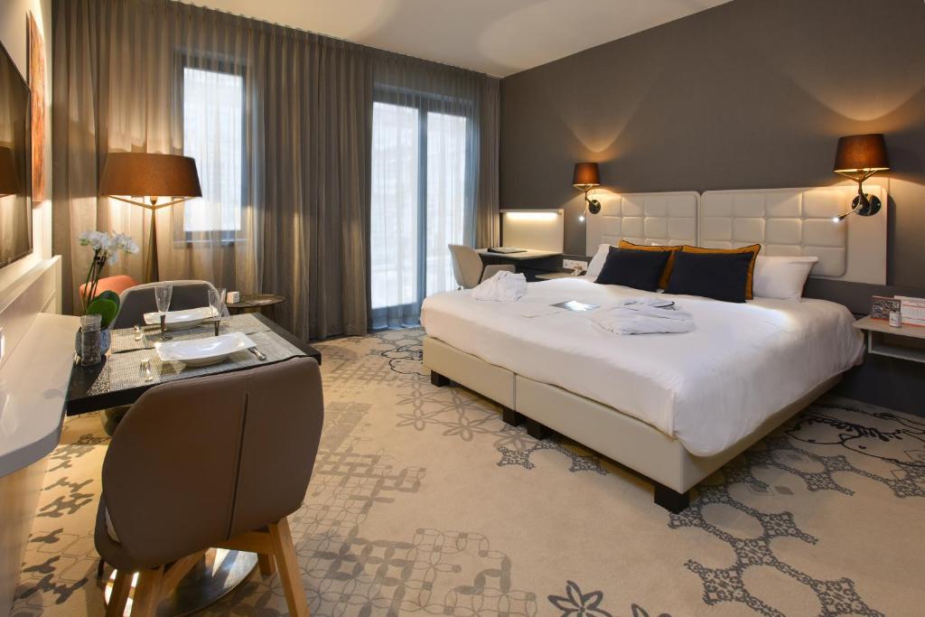 a hotel room with a large bed and a desk at Martin's All Suites in Louvain-la-Neuve