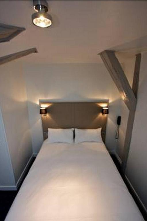 Ce lit se trouve dans une petite chambre dotée d&#39;un couvre-lit blanc. dans l&#39;établissement Hôtel Henri IV, à La Rochelle