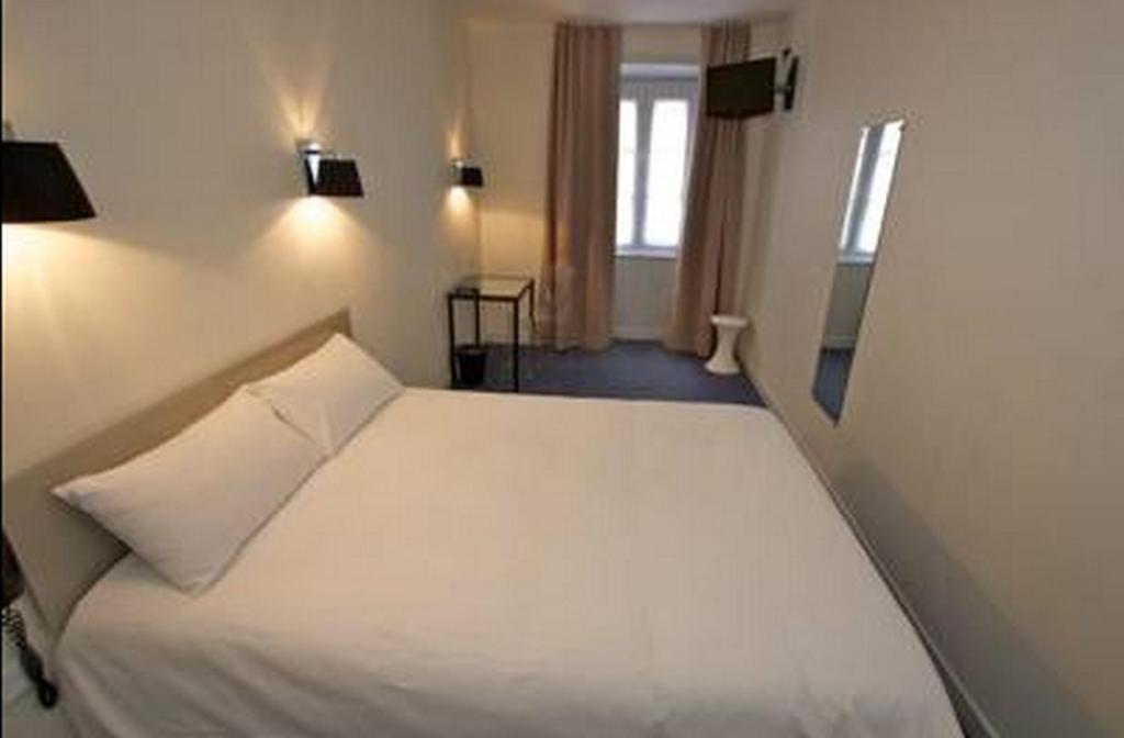 - une chambre avec un lit blanc et une fenêtre dans l&#39;établissement Hôtel Henri IV, à La Rochelle