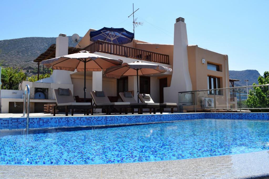 a villa with a swimming pool with chairs and umbrellas at Ida villa in Hersonissos