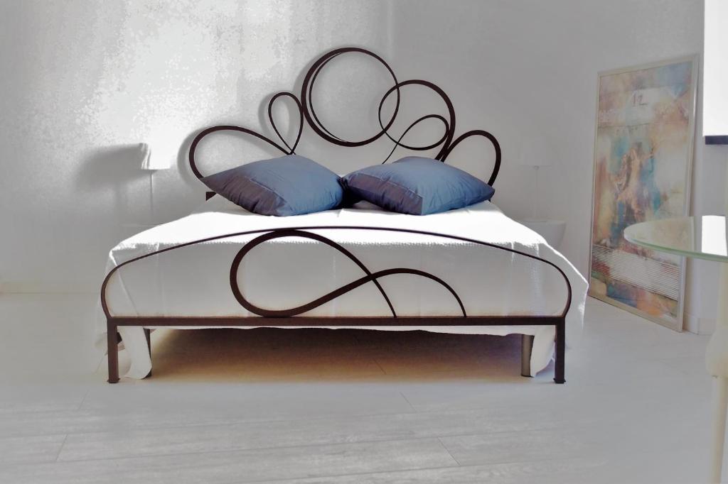 a bed with a black metal frame and blue pillows at La Dorata in Trieste