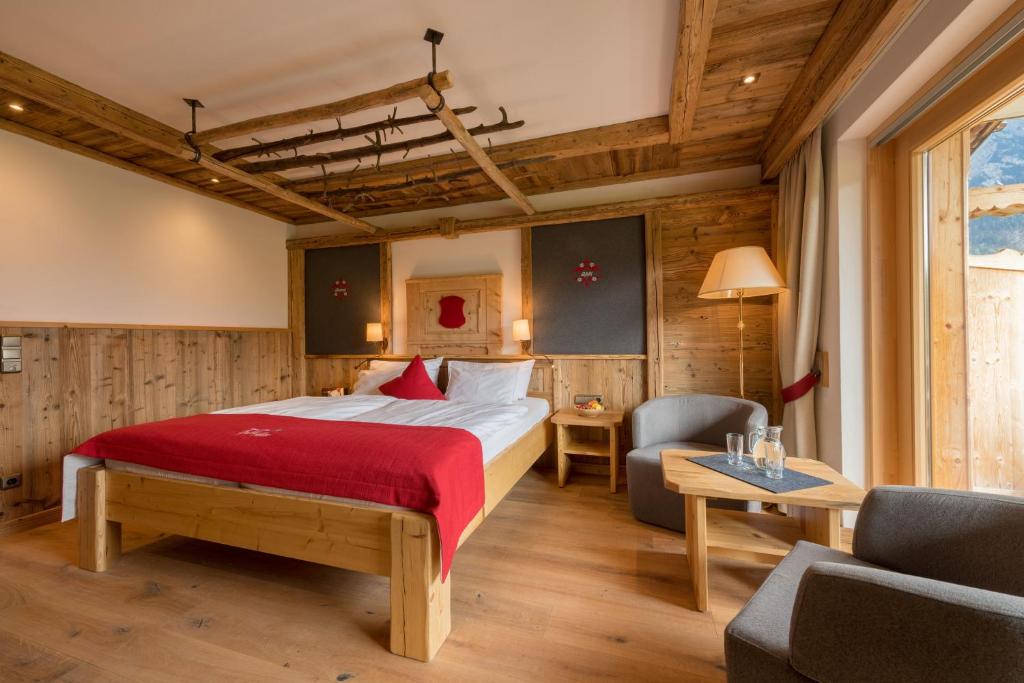 ミッテンヴァルトにあるGröbl-Almのベッド、ソファ、テーブルが備わるホテルルームです。