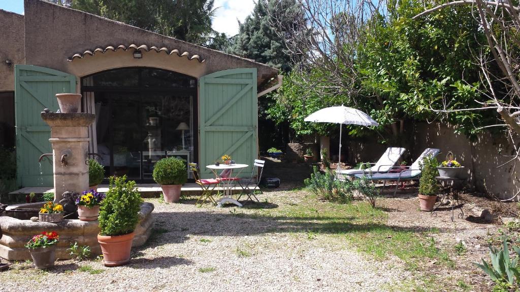 a garden with a table and chairs and an umbrella at L'Oustalet in La Tour-dʼAigues