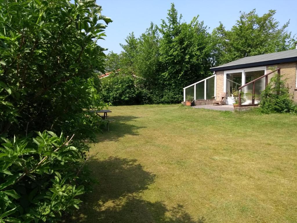 a garden with a house and a grass yard at Zeealsem in Ballum