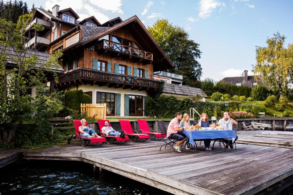 a group of people sitting around a table on a deck at Seevilla Leitner in Seeboden