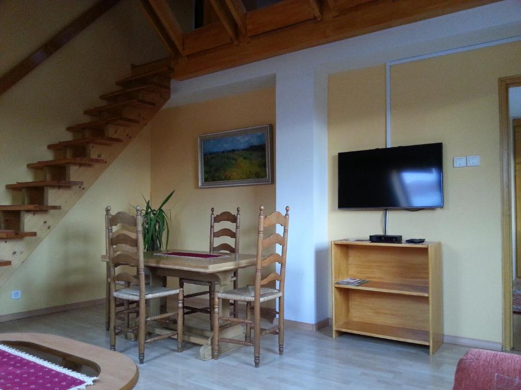 ein Esszimmer mit einem Tisch mit Stühlen und einem TV in der Unterkunft Szekszárd Apartman in Szekszárd