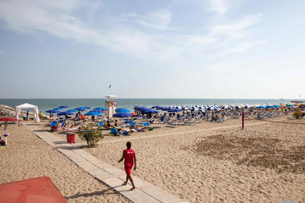 a man walking on a beach with a crowd of people at Hotel Valdor in Cavallino-Treporti