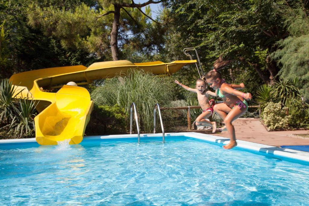 two girls jumping into a swimming pool at a water park at Hotel Valdor in Cavallino-Treporti