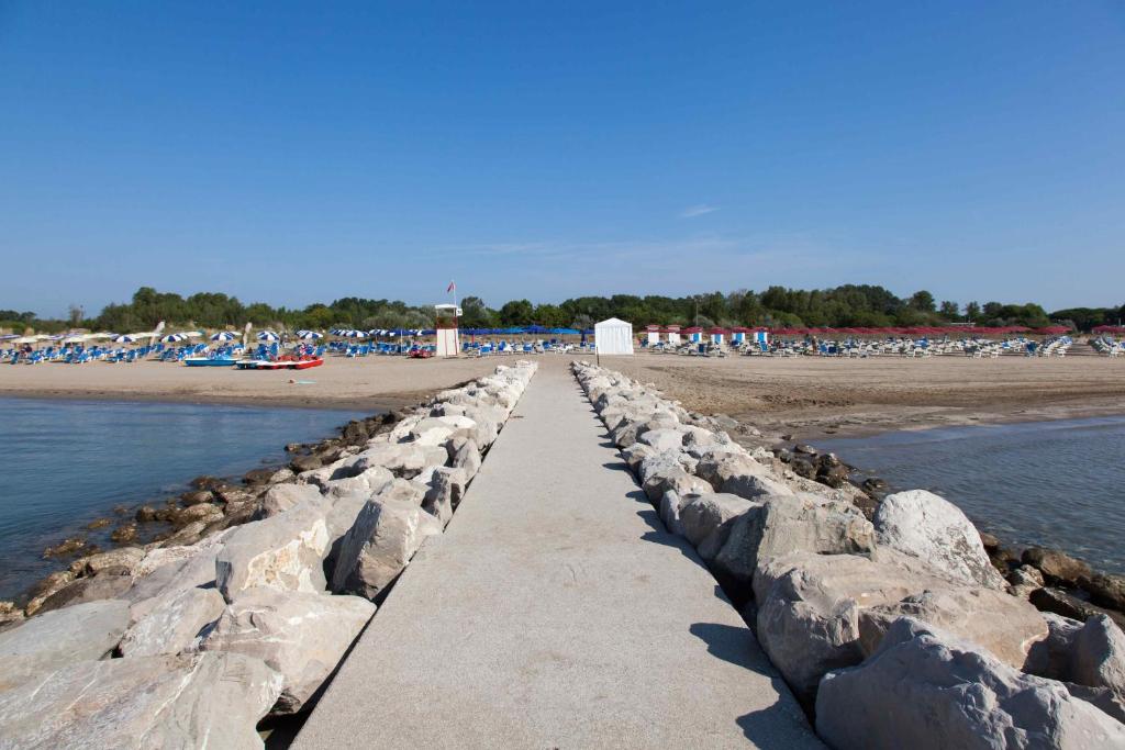 a retaining wall on the beach with a group of people at Hotel Valdor in Cavallino-Treporti