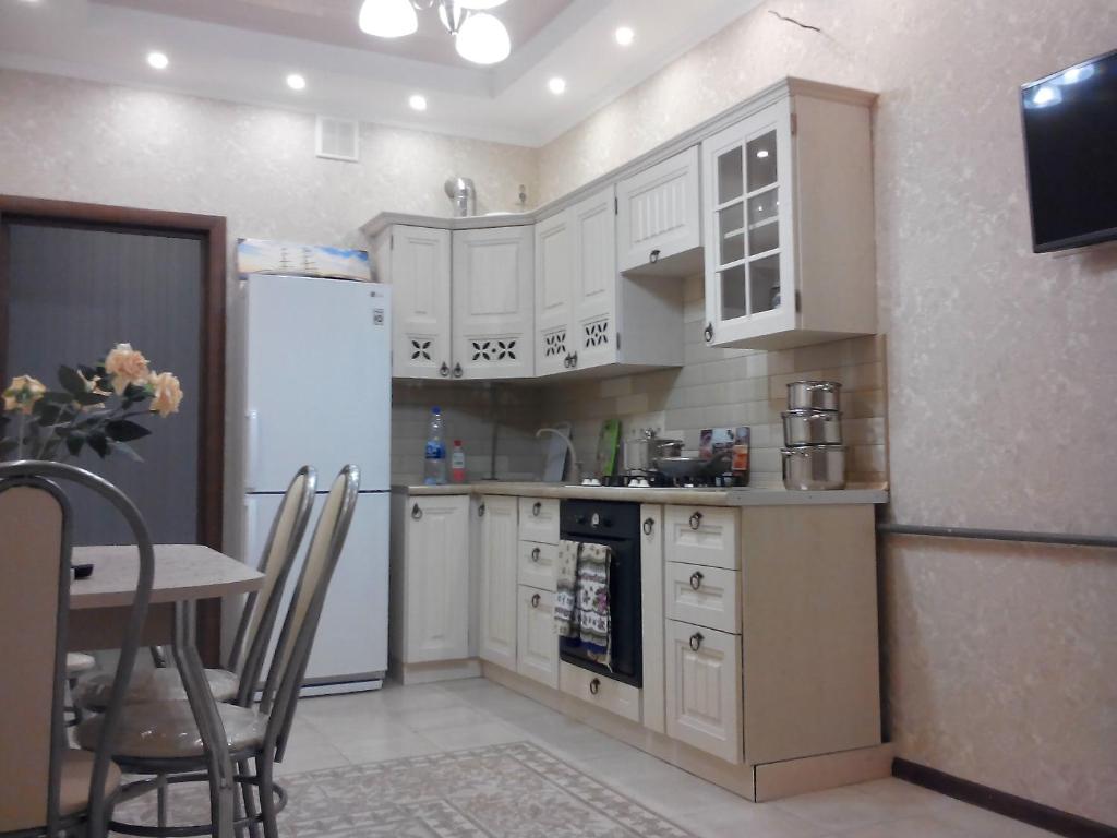 ゲレンジークにあるApartment on Turisticheskayaのキッチン(白いキャビネット、テーブル、冷蔵庫付)