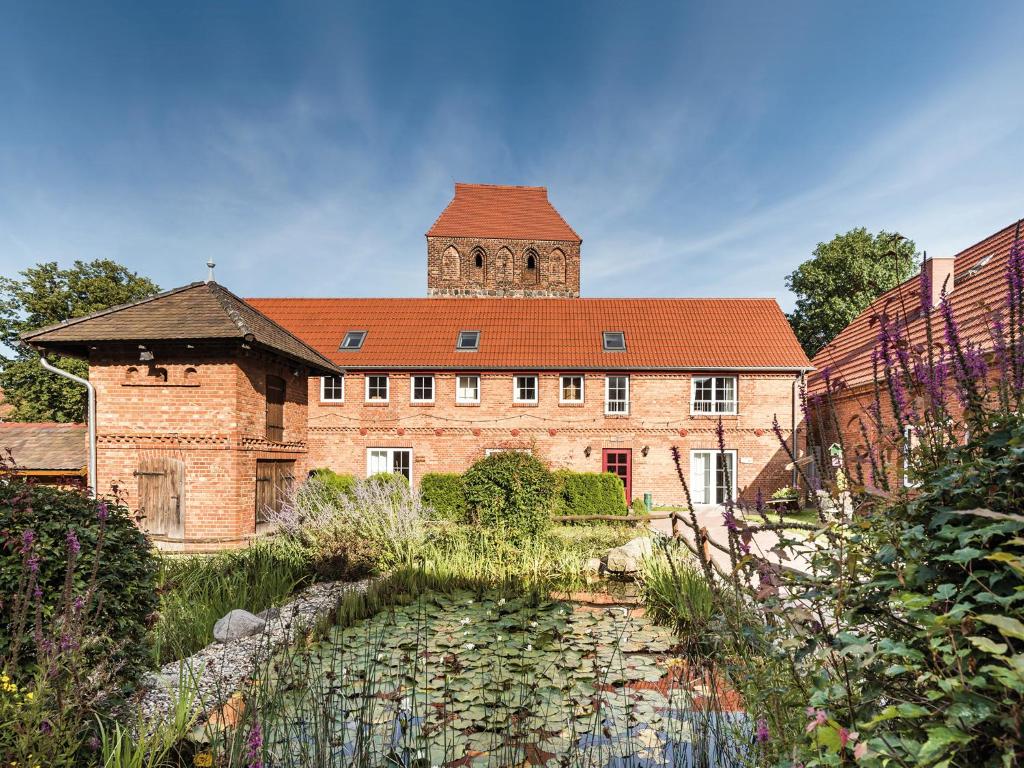 a large brick building with a pond in front of it at Landgasthof Jüterbog in Jüterbog