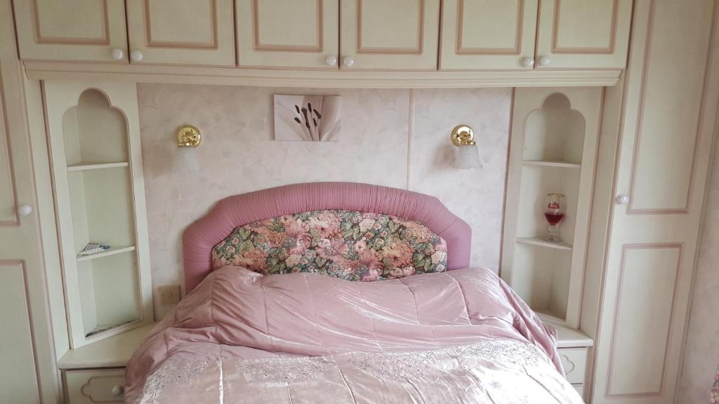 a bedroom with a pink bed and white cabinets at Static caravan in Chapel Saint Leonards