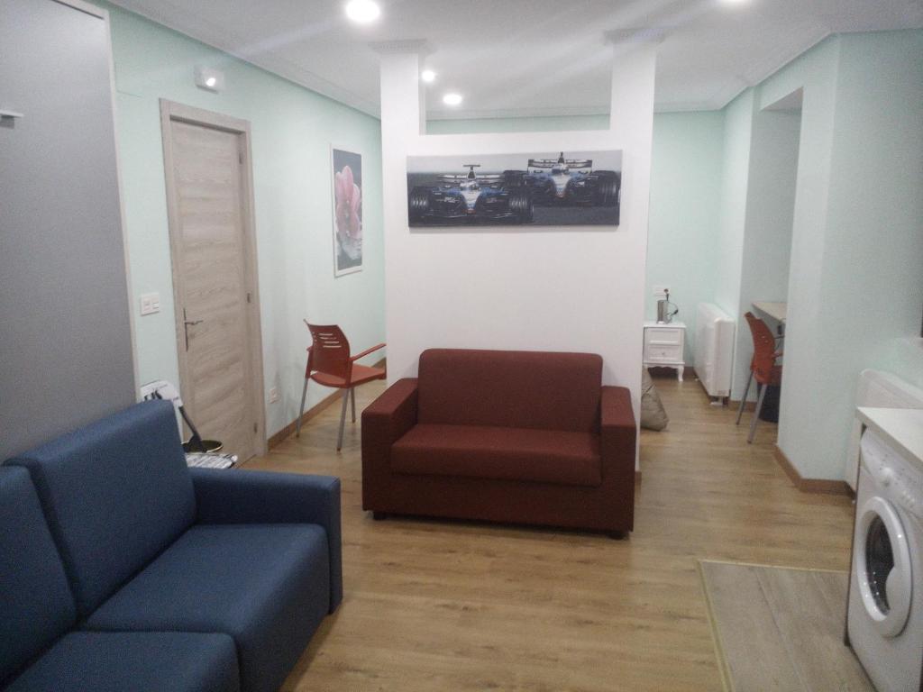 een woonkamer met een bank en een stoel bij Apartamentos Corazón del Húmedo in León