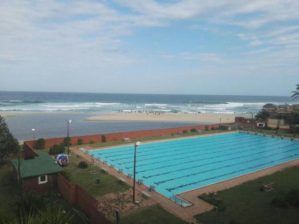 ein großer Pool neben einem Strand mit dem Meer in der Unterkunft Margate Boulevard 302 in Margate