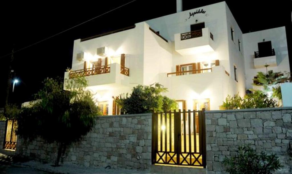 a white building with a fence in front of it at Aerolithos in Adamantas