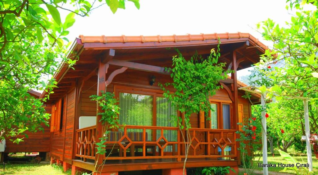 a wooden cabin with a balcony in the trees at Baraka House in Cıralı