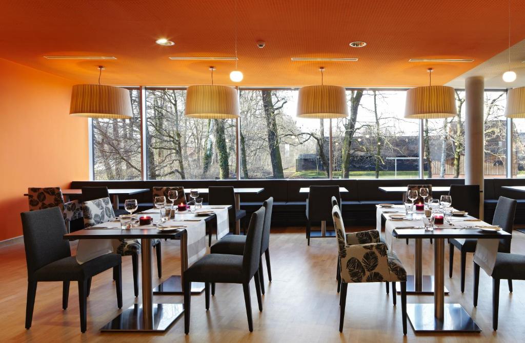 ein Esszimmer mit Tischen und Stühlen und Fenstern in der Unterkunft Spreewald Thermenhotel - Spreewald Therme GmbH in Burg
