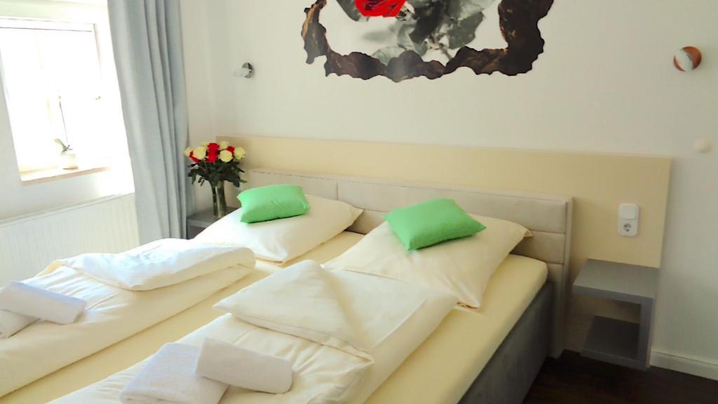 Hotel Stadt Soltau في سولتو: سريرين في غرفة مع وسائد خضراء وبيضاء