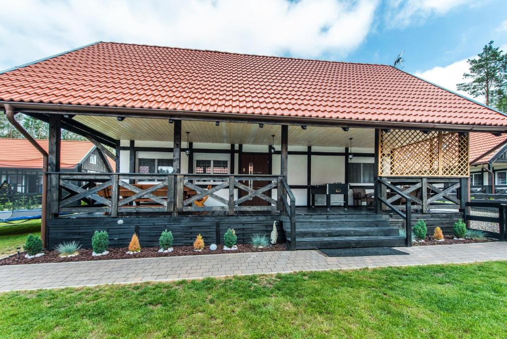 a house with a wooden porch and a red roof at Domek U Justyny in Załakowo