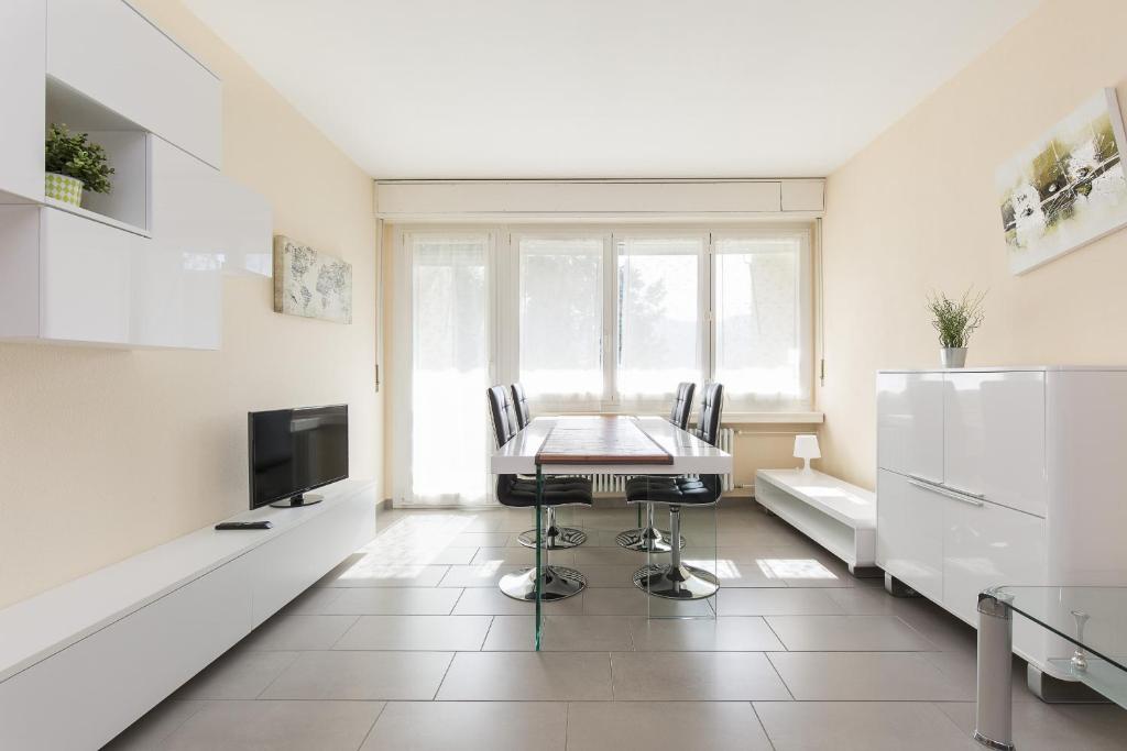uma cozinha com uma mesa e cadeiras e uma televisão em Girasole by Quokka 360 - quiet two-bedroom apartment close to the centre em Lugano