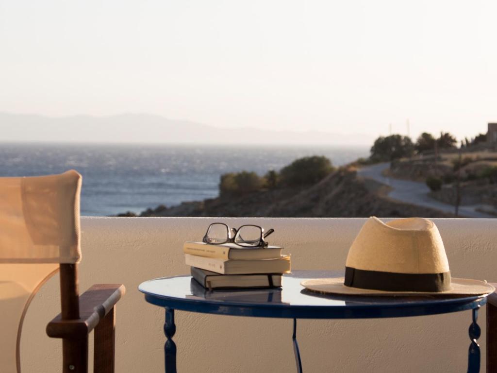 een tafel met boeken en een hoed en bril erop bij Meltemi Tinos in Agios Romanos