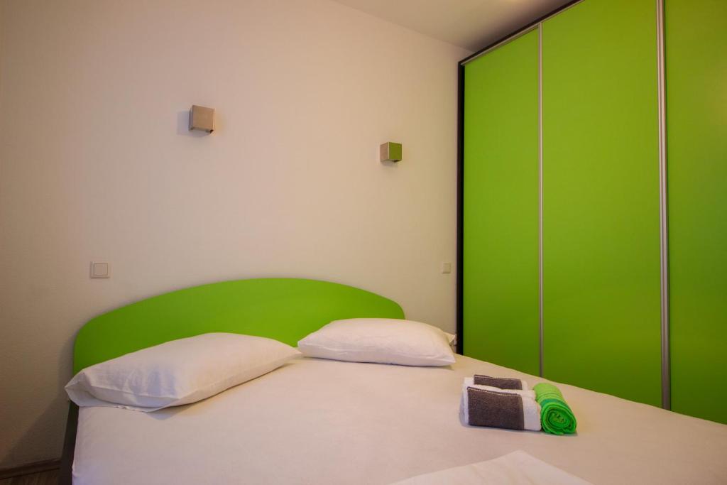 1 dormitorio con cabecero verde y 1 cama en Apartments Hajdi, en Duće