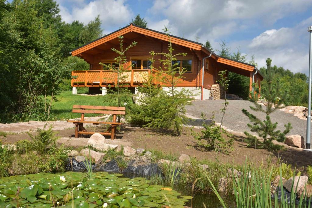 domek z bali ze stawem przed nim w obiekcie Erzgebirgsholzhaus am Lugstein w mieście Altenberg