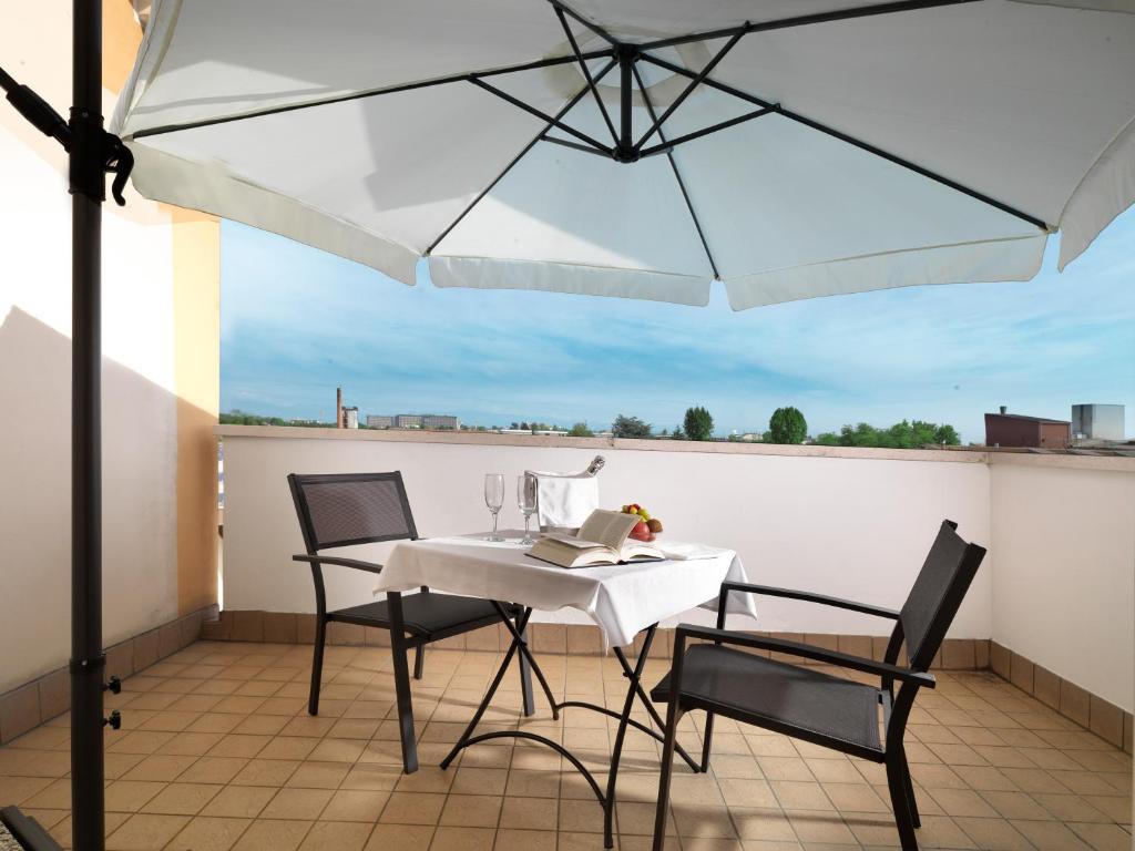 a table and chairs on a balcony with an umbrella at Hotel Al Pino Verde in Camposampiero