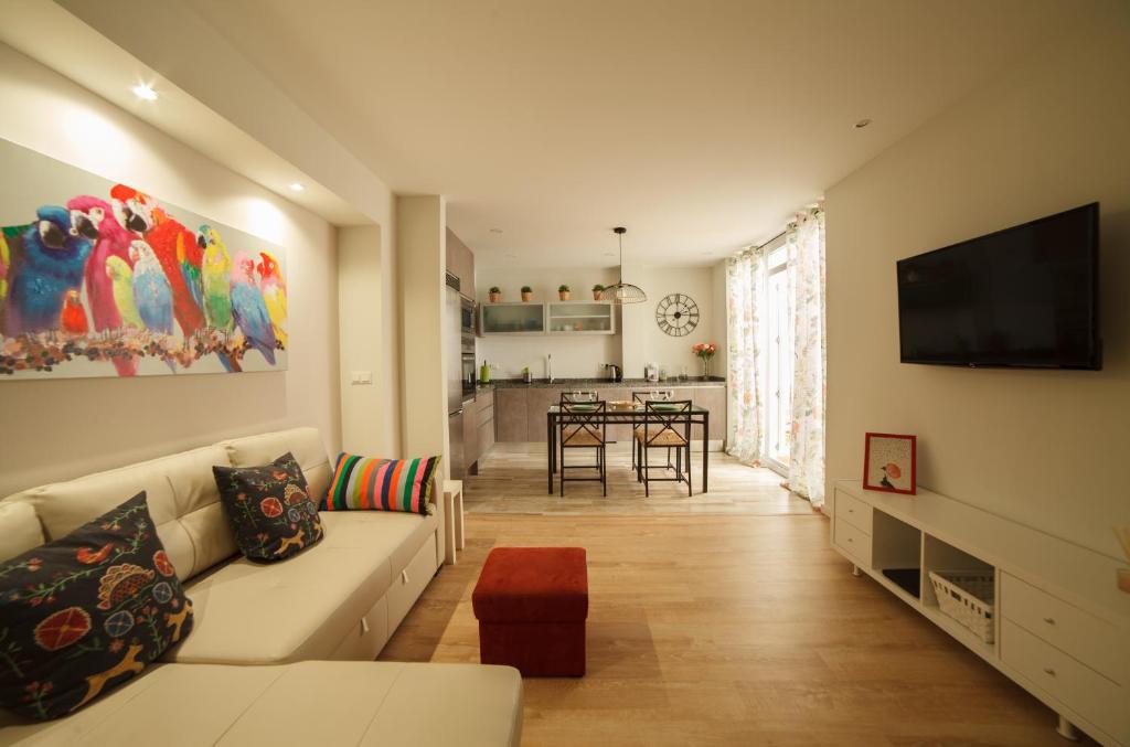uma sala de estar com um sofá branco e uma televisão em Carlota em Alicante