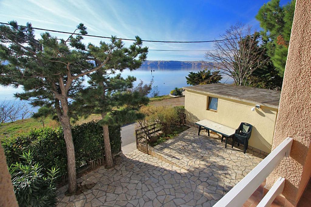 una panchina seduta accanto a una casa con vista sull'acqua di Beachfront House Ivana with Pool a Cesarica