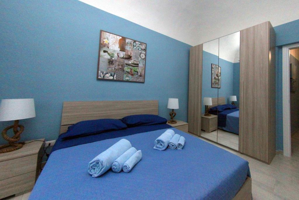 a blue bedroom with a large bed with blue walls at Patrì House in Catania