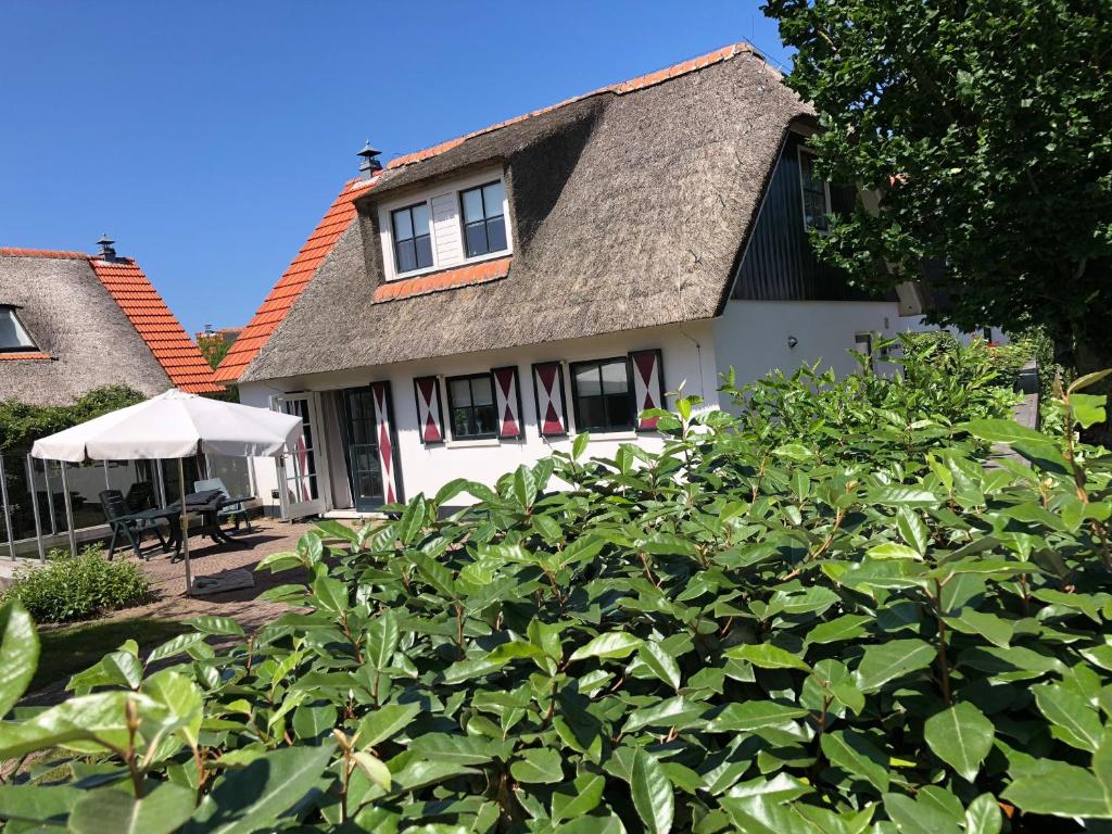 een wit huis met een grijs dak bij Villa Buiten 58 in Callantsoog