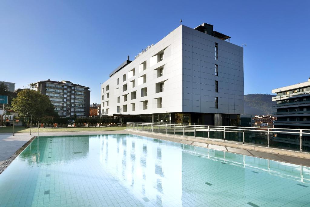 une grande piscine en face d'un bâtiment dans l'établissement Occidental Bilbao, à Bilbao