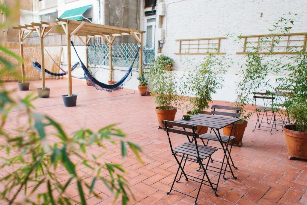 een patio met een hangmat en een tafel en stoelen bij ZOOROOMS Boutique Guesthouse in Barcelona