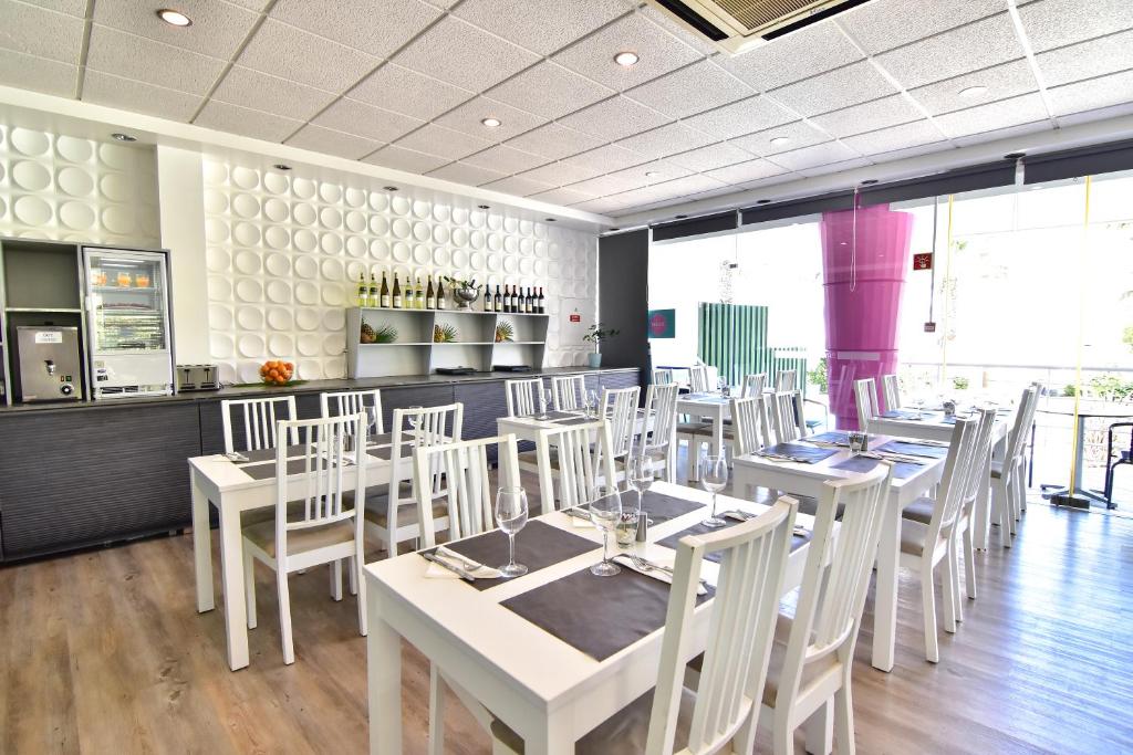 a dining room with white tables and white chairs at Bayside Salgados in Albufeira