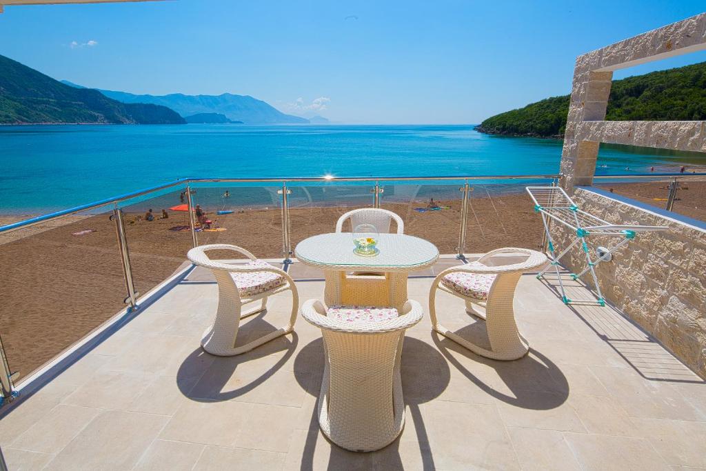 a table and chairs on a balcony overlooking a beach at Manda 107 Mansion in Budva