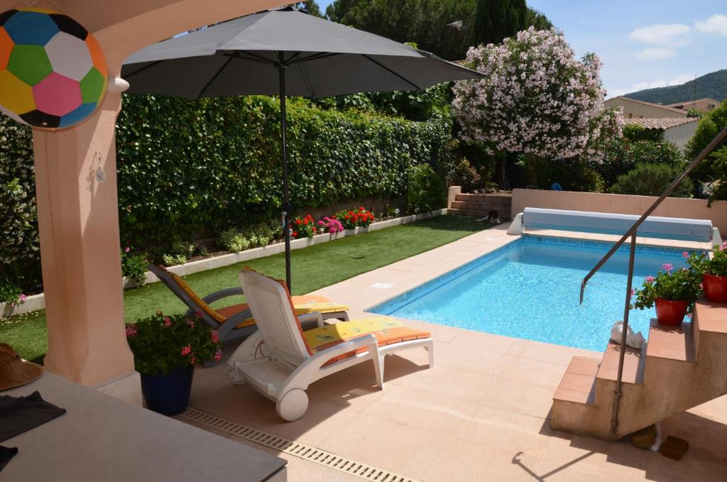 - une piscine avec un parasol et une chaise dans l'établissement Studio Hirondelle, à Roquebrune-sur Argens