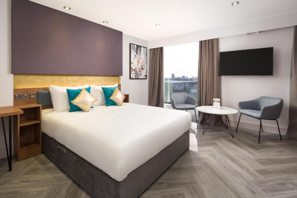 a hotel room with a large bed and a desk at Roomzzz London Stratford in London