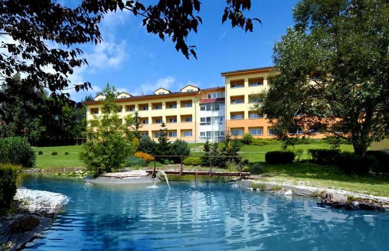 un bâtiment avec piscine d'eau en face d'un bâtiment dans l'établissement Exclusive HOTEL Lipno Wellness & SPA, à Frymburk